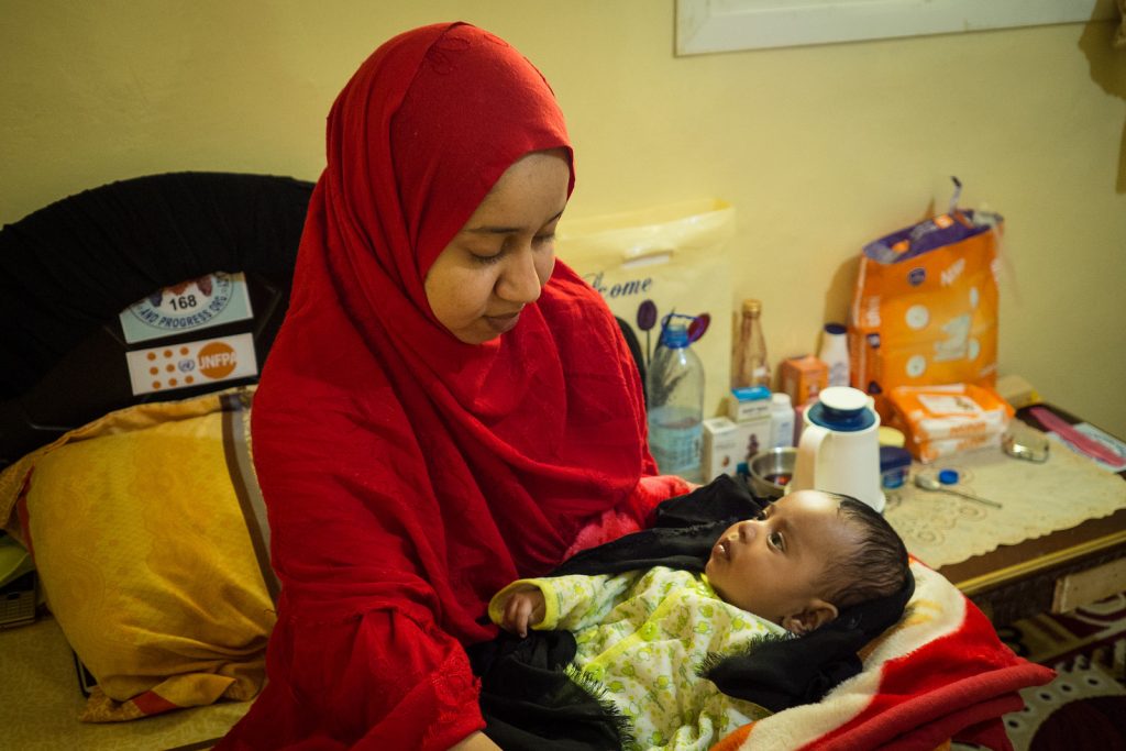 Aamiina sits in her room at the shelter home in Hargeisa, holding her young son.